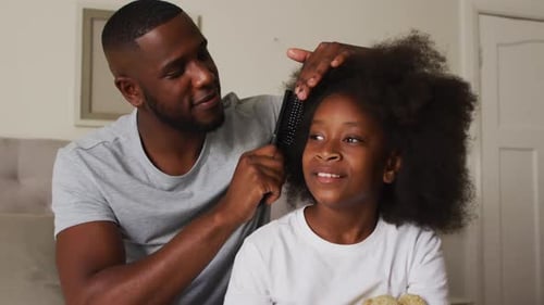 Man Combs Girl's Hair Indoors