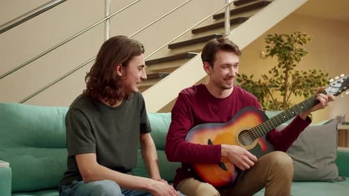 Young Adults Playing Guitar on Couch at Home