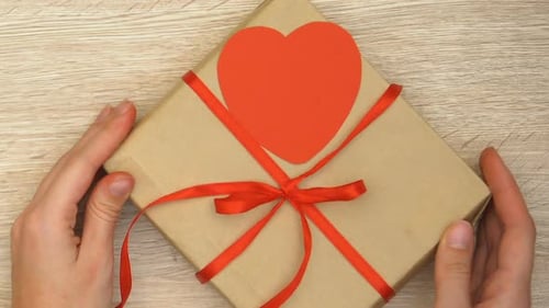 Hands Present a Beautiful Gift with Red Ribbon