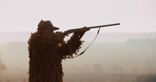 Porträt des Jägers in Jagdausrüstung. Silhouette des Menschen im Abendlicht: Finden Sie das Ziel und die Ziele