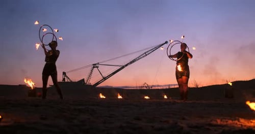 Eine Gruppe von Männern und Frauen Feuershow bei Nacht im Sand vor dem Hintergrund von Feuer und Turm