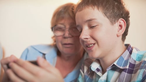 Teenager and Grandmother Look at Phone Together