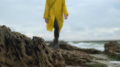 Woman in Yellow Raincoat Walking on Beach
