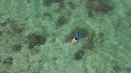 Aerial Slowmotion Shot of a Young Woman Snorkeling in a Clear Blue Sea Water