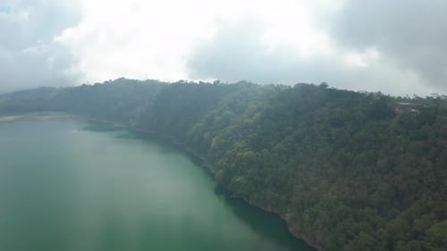 Drone Over Green Forest And Lake Under Cloudy Sky