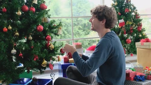 Young Adult Decorating Christmas Tree with Ornaments