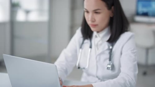 Young Adult Doctor Types on Laptop in Clinic
