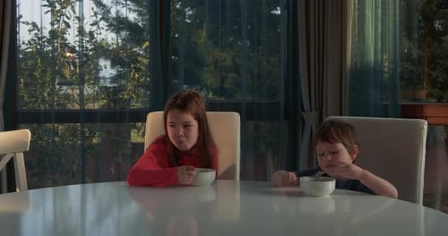 Brother and Sister Eating Cereal at Home