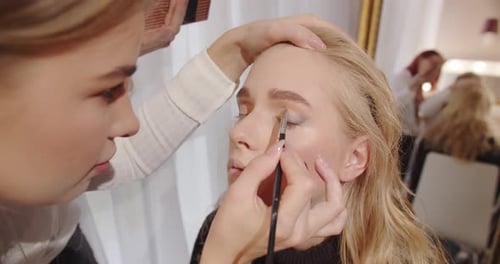 Woman Applying Eye Makeup to Another Woman Indoors