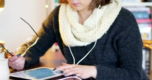 Woman Using Tablet at Home Wearing Headphones