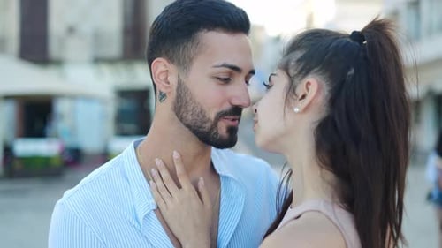 Smiling Hispanic Couple Talking and Kissing on Street
