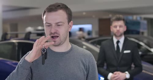 Close-up Portrait of Satisfied Caucasian Man Standing in Car Dealership with Keys From New