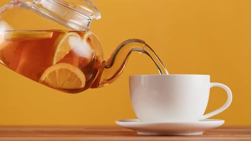 Verter té negro cítrico sobre fondo naranja