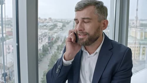 Man Talking on Phone Near Office Window