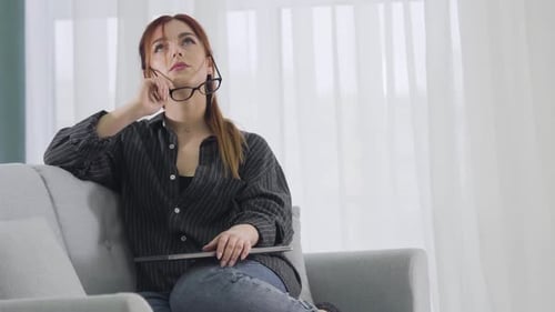 Woman Relaxes on Sofa Before Using Laptop
