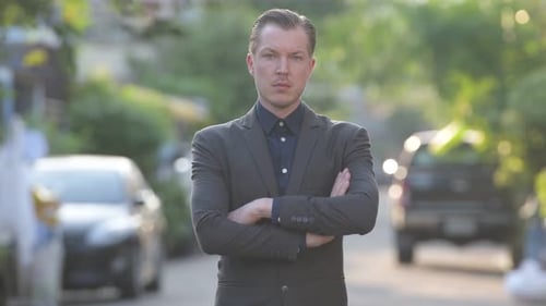 Smiling Man in Suit Stands on Suburban Street