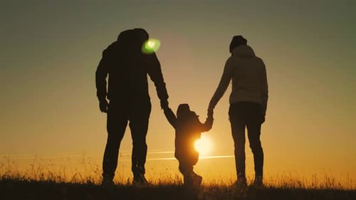 Family Holding Hands in Silhouette at Sunset