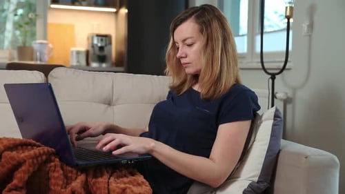 Woman using Laptop Computer on Couch Indoors