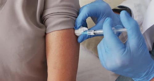 Close up of male doctor giving covid-19 vaccine to woman at home