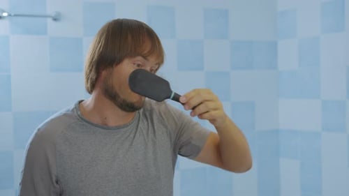 Man Brushing Hair Looks Shocked at Hair Loss