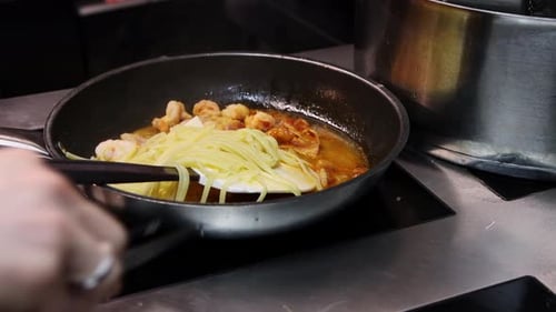 Chef cooking shrimp and spaghetti in pan