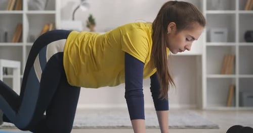 Woman Exercising on Mat Doing Donkey Kicks