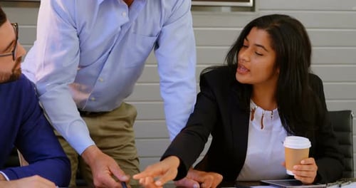 Executives discussing over blueprint in conference room at office