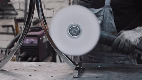 Ein Arbeiter, der ein kreisförmiges Metalldetail mit einer großen Poliermaschine poliert