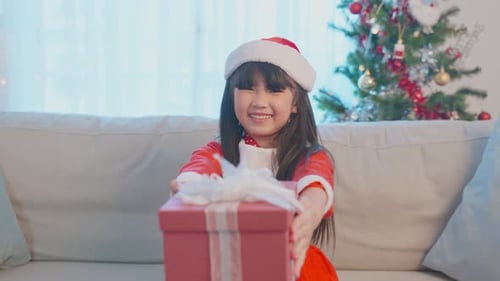Girl Smiles Giving Christmas Gift in Home Setting