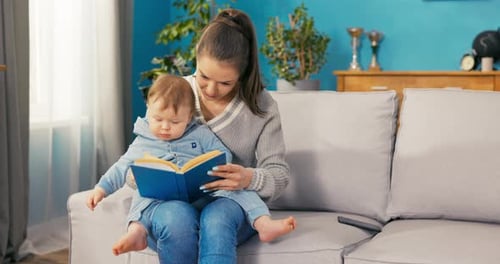 Mother and Child Reading Book on Sofa