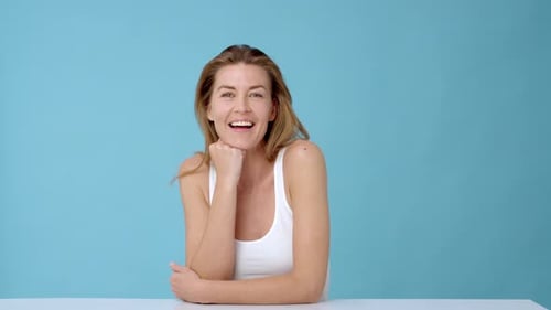 Smiling Woman Posing in Front of Blue Background