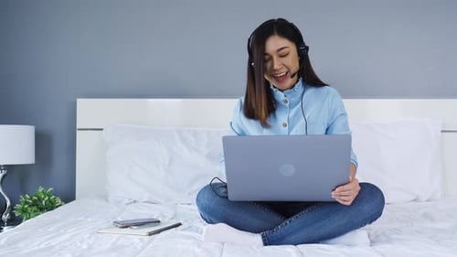 Woman Using Laptop for Video Call on Bed