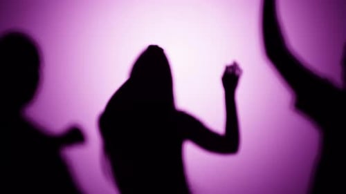 Silhouettes of Young Adults Dancing in Purple Light