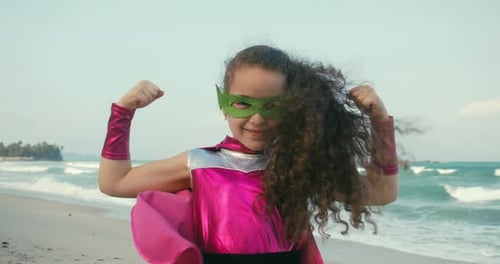 Jolie petite fille dans un costume de super-héros vêtue d'une cape rose et d'un masque de héros vertUn enfant joue un