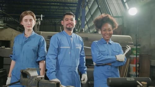 Gemischtrassige Arbeiter arbeiten zusammen und bringen ihre glückliche Arbeit in einer mechanischen Fabrik zum Ausdruck.