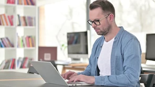 Man Working on Laptop Smiling in Office
