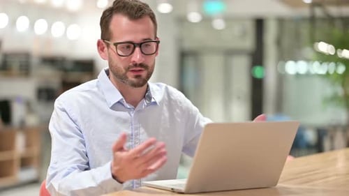 Businessman Talking on Video Call on Laptop in Office