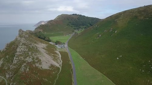 Forward tracking aerial over the Valley of Rocks, Lynton, Devon. Car park and a game of cricket bein