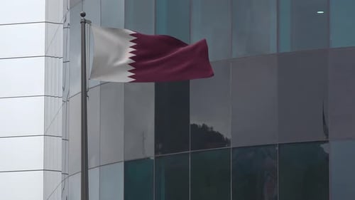 Waving Flag of Qatar on Flagpole with Modern Building Background