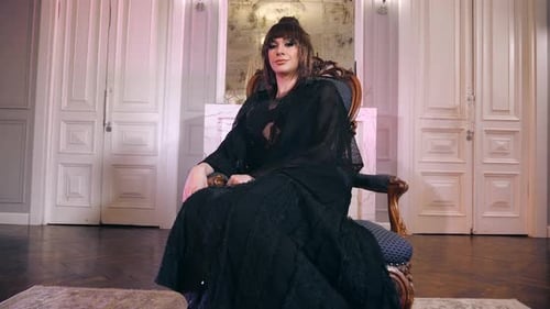 Woman in Elegant Black Dress Poses in Ornate Chair