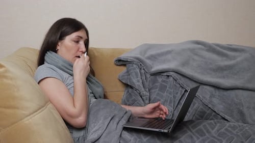 Woman Uses Laptop While Lying Sick on Couch