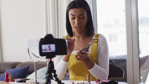 Vloguera mestiza de género fluido que graba un vlog de maquillaje en casa