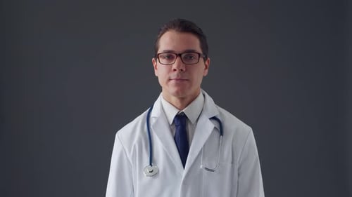 Studio portrait of young professional medical doctor standing over grey background