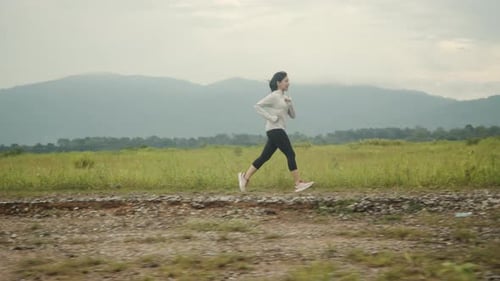Athletic Woman Runs on Trail Through Green Field