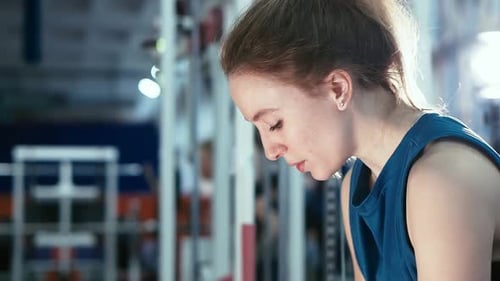 Side View, Portrait a Muscular Athlete Girl Engaged in Lifting Weights on the Simulator