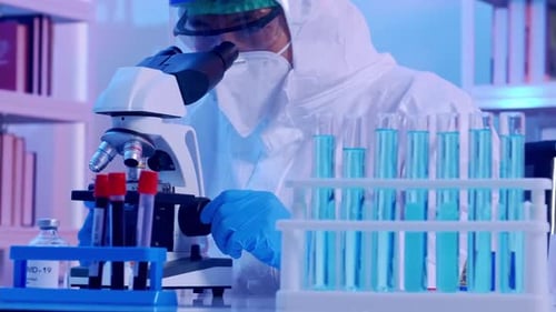 Scientist in Lab Examining Samples Under Microscope