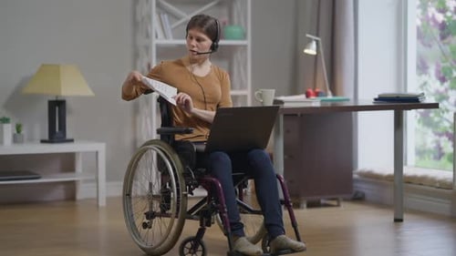 Woman in Wheelchair Using Laptop and Charts