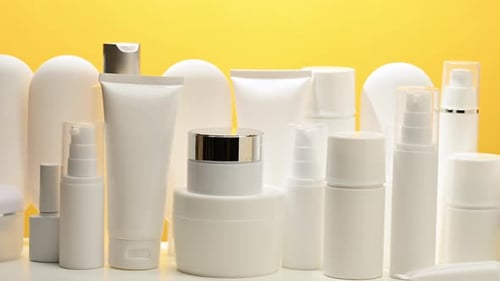 jar, bottle and empty white plastic tubes for cosmetics on a yellow background