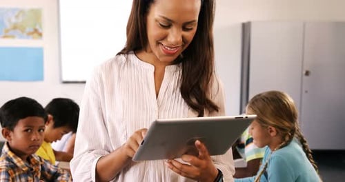 Teacher Uses Tablet With Students In Classroom