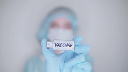 The doctor holds the vaccine in his hand in an ampoule